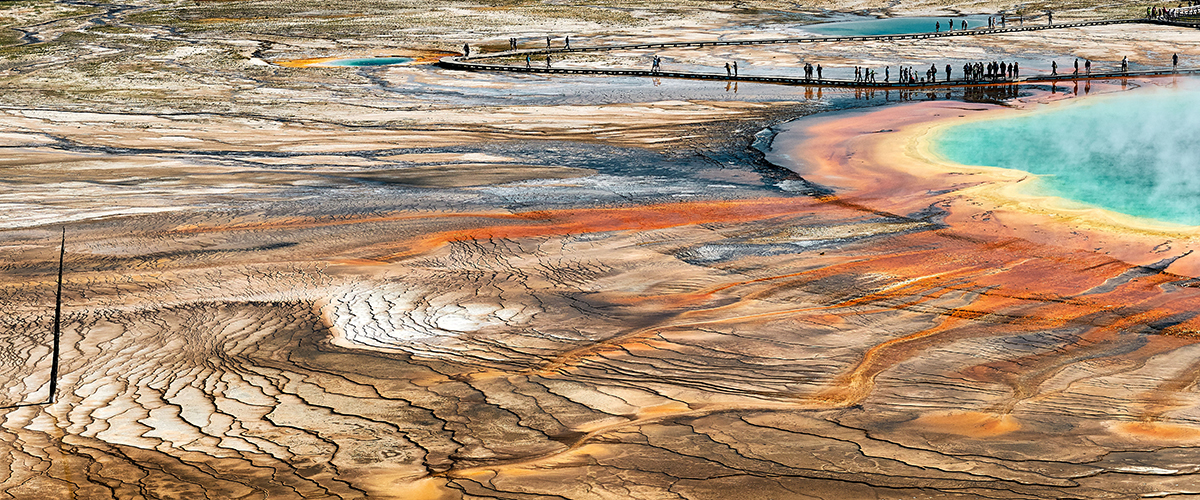 Yellowstone in July: What to Expect and How to Make the Most of It 3 Aerial view of the colorful Grand Prismatic Spring with boardwalk visitors in Yellowstone in July