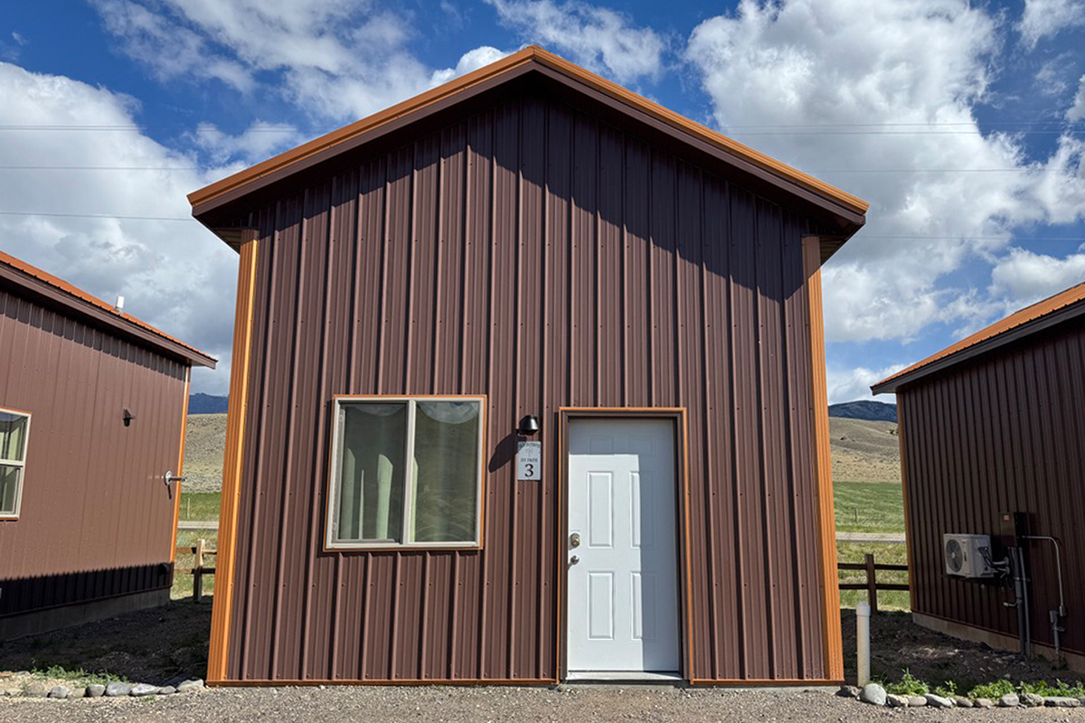 Yellowstone in July: What to Expect and How to Make the Most of It 10 Exterior of a rustic cabin with a white door and mountain views at Old Faithful RV Park near Cody Wyoming