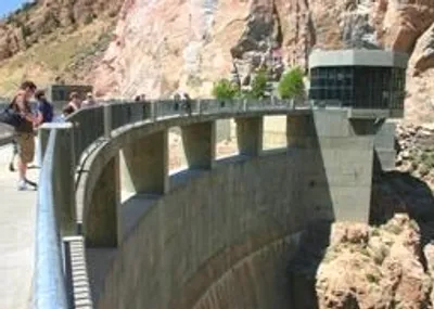 Visitors walking across the top of the Buffalo Bill Dam with dramatic red canyon walls on both sides near Cody Wyoming