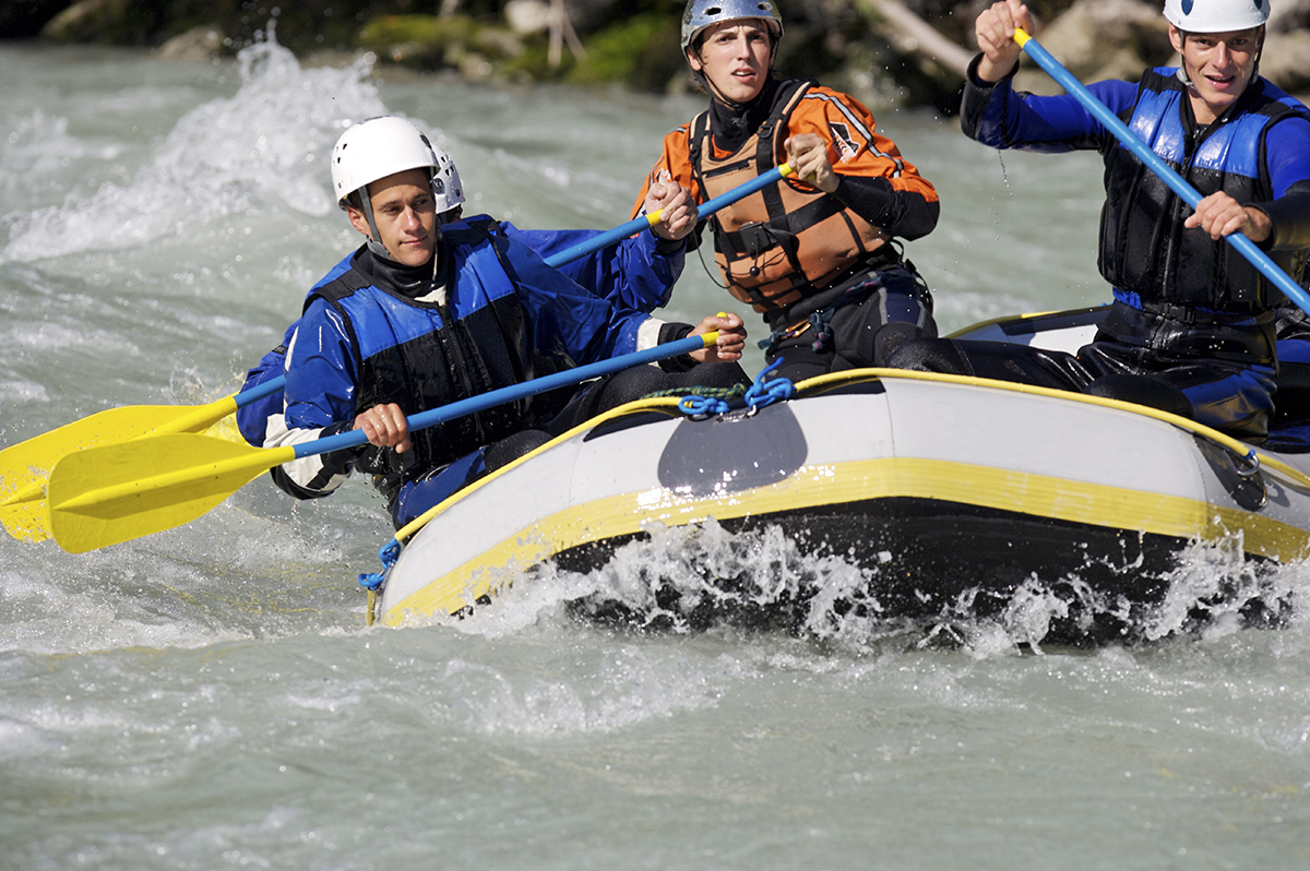 Three rafters paddling through whitewater rapids on a day trip from Cody Wyoming on the Shoshone River