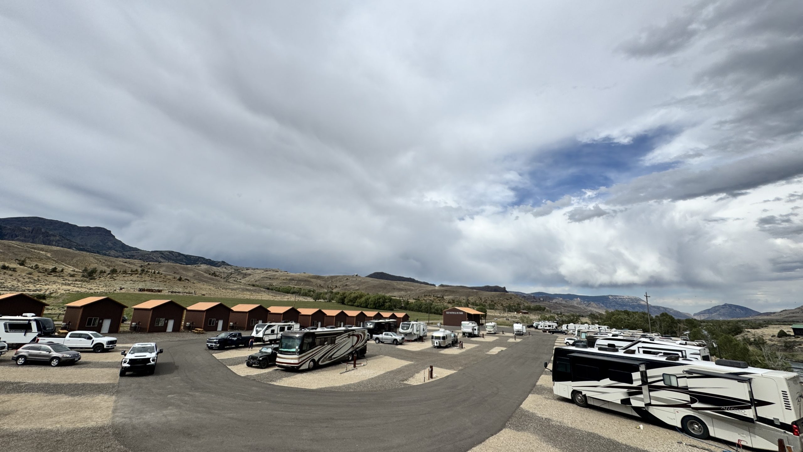 Yellowstone Group Camping: Why Old Faithful RV Park Is Perfect for Your Next Reunion or Rally 2 Wide view of Old Faithful RV Park showing cabin row and RV sites under a cloudy sky