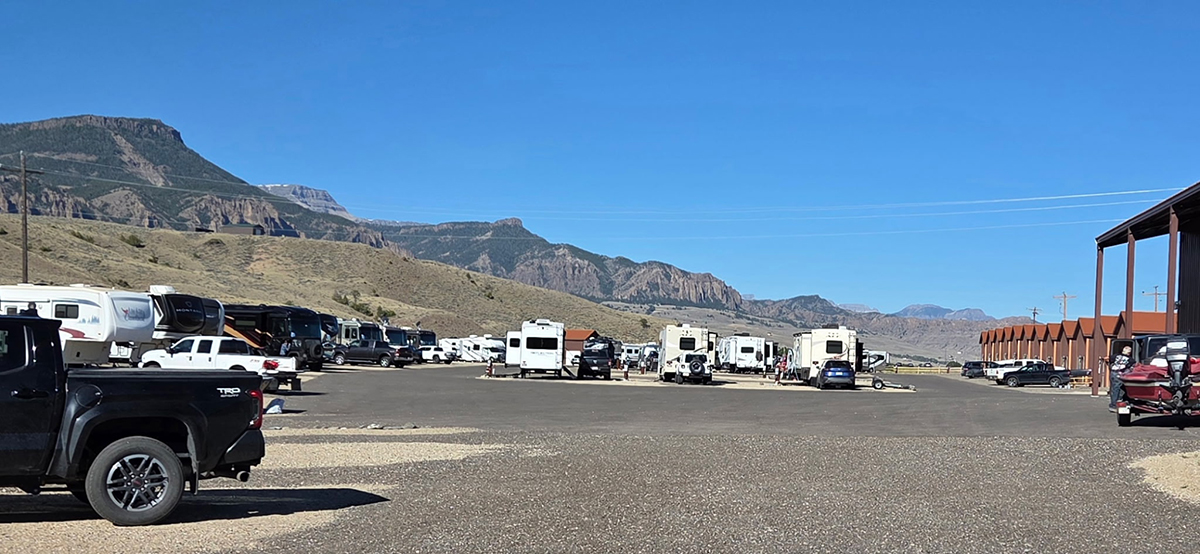 Row of RVs and trucks parked at full hookup sites with mountain views