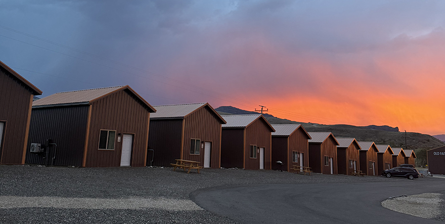 Yellowstone Group Camping: Why Old Faithful RV Park Is Perfect for Your Next Reunion or Rally 7 Row of rustic cabins at Old Faithful RV Park under an orange sunset sky
